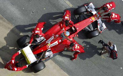 Fernando Alonso, a bordo de su Ferrari, es atendido por los operarios de la escuder&iacute;a italiana.