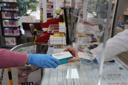 Un farmacéutico vende una caja de Paracetamol en su farmacia.