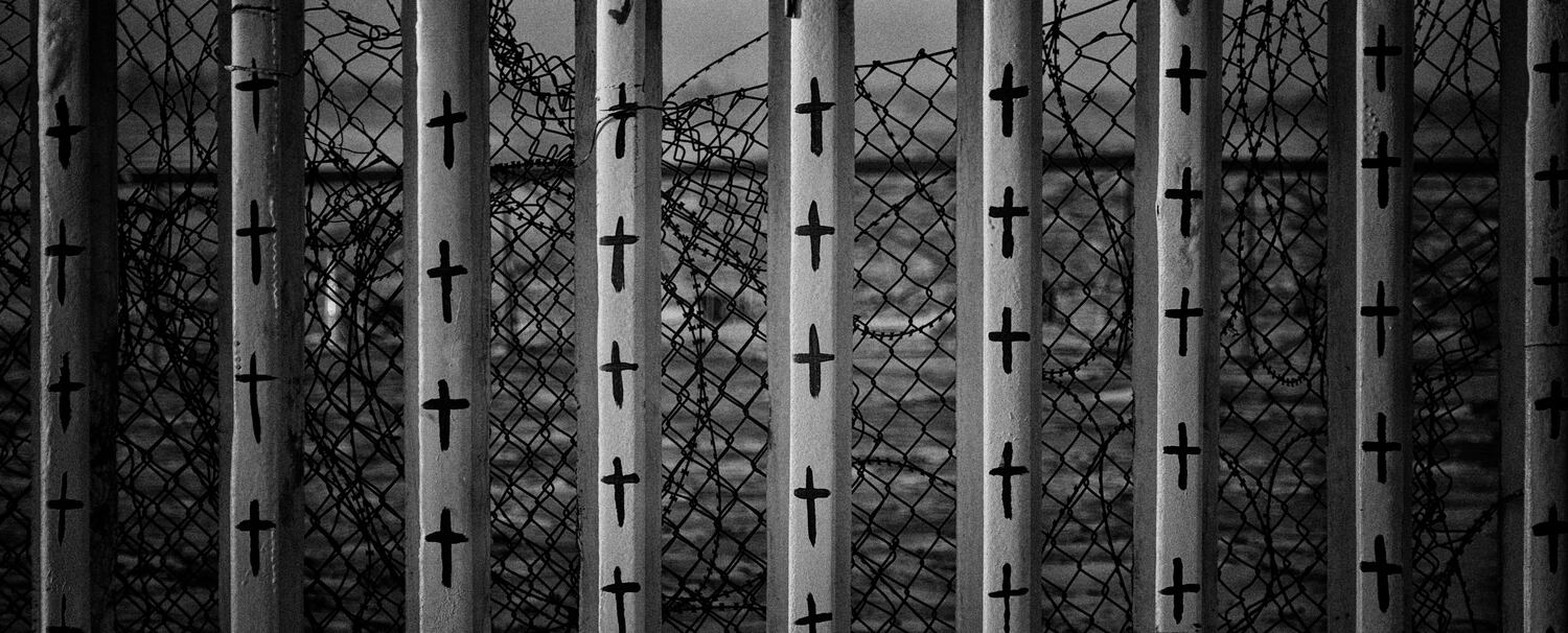 Cruces pintadas sobre el muro fronterizo representando a los migrantes fallecidos en su intento por cruzar.