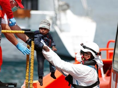 Un niño rescatado de una patera en el Mediterráneo por agentes de salvamento marítimo es bajado a tierra firme en el puerto de Arguineguín, Gran Canaria, el 31 de marzo de 2020.