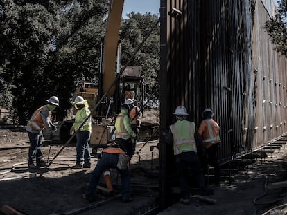 Trabajadores levantan el nuevo muro fronterizo en el desierto de Baja California.