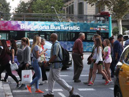 Paseantes en una céntrica calle de Barcelona, con un autobus turístico al fondo