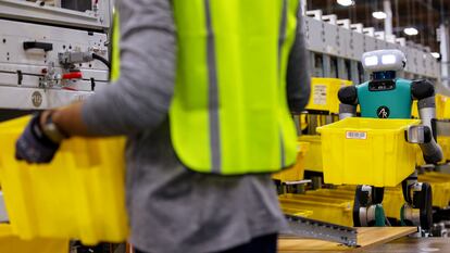 Operario de Amazon con robot en uno de sus centros logísticos.