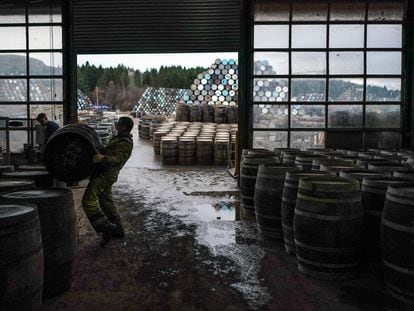 Un trabajador levanta una barrica de whisky en la destilería Speyside Cooperage, en Craigellachie, Escocia.