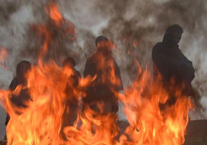 Un grupo de trabajadores afganos se calienta en torno a un fuego, en Kabul (Afganistán).