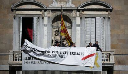 Trabajadores del Palau colocan una pancarta encima de la ya existente con el mismo lema pero con un lazo blanco tachado con una raya roja.