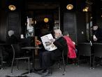 A Parisian reads Le Monde newspaper with a drink at a cafe terrace in Paris, Wednesday, May, 19, 2021. Cafe and restaurant terraces, museums, cinemas and theaters are reopening their doors after a shutdown of more than six months in the first stage of a government strategy to incrementally lift restrictions to stave off COVID-19, and give the French back some of their signature "joie de vivre." (AP Photo/Francois Mori)