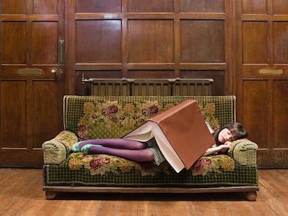 Una adolescente durmiendo con un gran libro sobre ella.