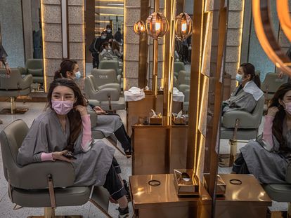 Dos mujeres con máscaras en un salón de belleza de Wuhan (China), este martes.