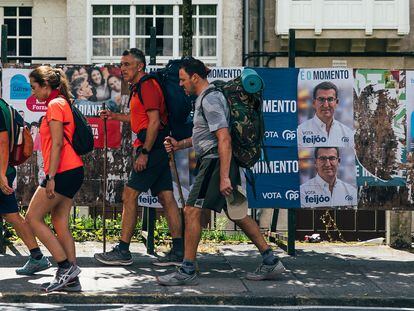 Un grupo de peregrinos pasa delante de carteles electorales, este sábado en Santiago de Compostela (A Coruña).