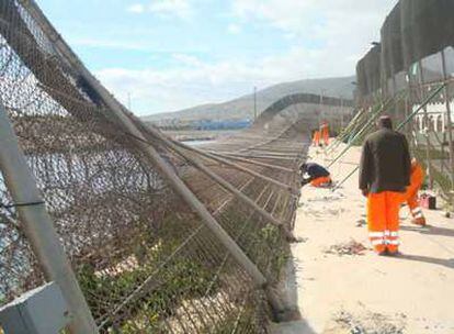 Unos operarios trabajan para reparar la valla de Melilla que ha caído por los fuertes vientos