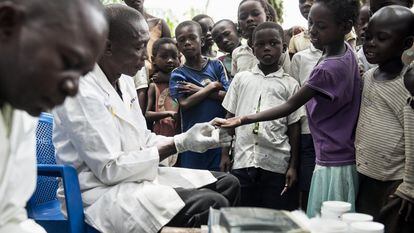 Dos enfermeros toman muestras de sangre a niños en Yalikombo, Congo, para detectar posibles casos de enfermedad del sueño.