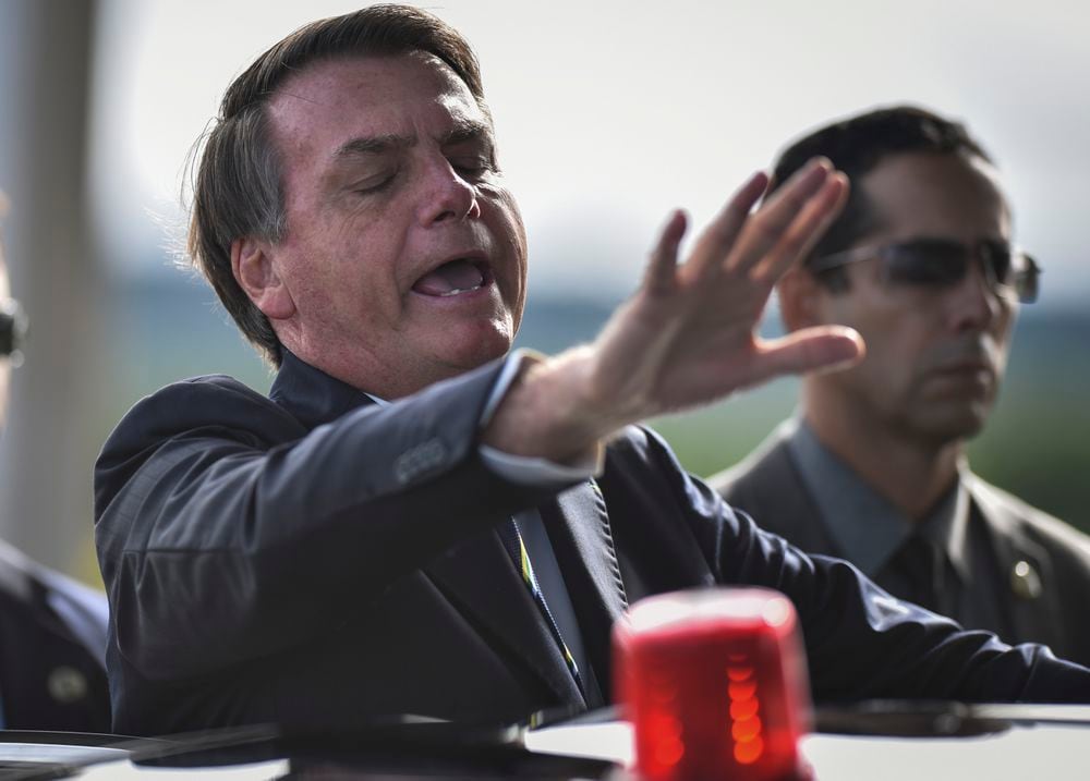 El presidente de Brasil, Jair Bolsonaro, saluda a partidarios y periodistas en la previa de una rueda de prensa dedicada al coronavirus celebrada en el palacio de Planalto, el viernes 27 de marzo.