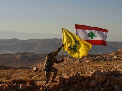 Un miliciano de Hezbol&aacute; planta las banderas libanesa y de la milicia tras expulsar a Al Nusra de los arreales de la localidad libanesa de Arsal