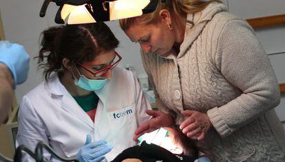 Un madre ayuda a su hijo en el dentista solidario de la Ca&ntilde;ada Real, en Madrid. 