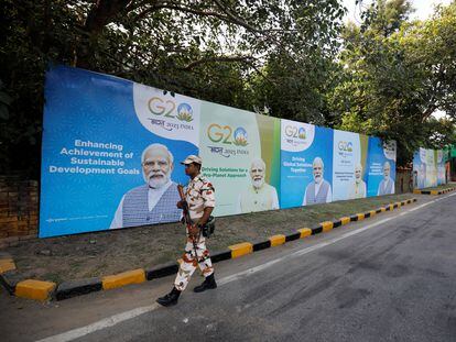 Un miembro de las fuerzas de seguridad patrulla una calle de Nueva Delhi delante de una serie de cartéles que retratan al primer ministro de la India, Narendra Modi.