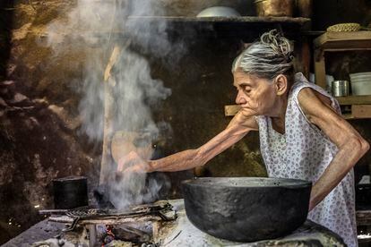 Adolfina Rojas Zaldívar, cocina en su bohío de la comunidad de Fray Benito, Holguín. Sus hijos han construido para ella una casa aledaña de ladrillo con más comodidades, pero tanto ella como su esposo, Regino Rojas, prefieren seguir viviendo en el que ha sido su hogar toda la vida.