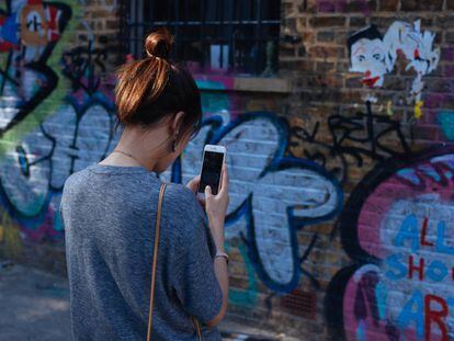 Una joven fotografía un grafiti en Brick Lane, Londres.