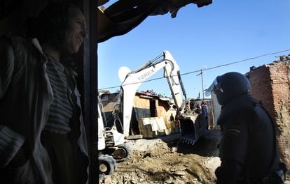 La operación, que ha durado toda la mañana, se ha desarrollado sin incidentes. Los voluntarios de las parroquias aseguran que "nunca" se había producido un derribo así en la zona. En la foto, un vecino contempla desde su casa los derribos, en presencia de un agente antidisturbios.