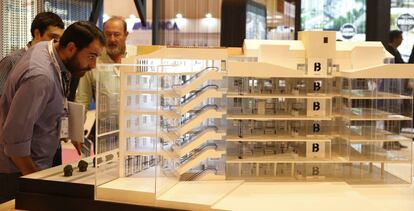 Visitantes del Salón Inmobiliario de Madrid observan una de las maquetas de viviendas expuesta en la feria.