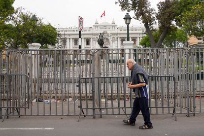 Las fuerzas de seguridad colocaron barreras para resguardar el Congreso de Perú. En la imagen, un hombre camina frente a la sede del Parlamento tras el anuncio de Castillo. 