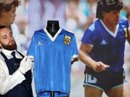 Un técnico de Sotheby's ajusta una camiseta de fútbol que usó el argentino Maradona contra Inglaterra en el Mundial de 1986.