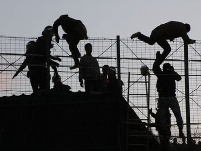 Inmigrantes subsaharianos saltando la valla de Melilla en presencia de agentes de la Guardia Civil el pasado mes de mayo.