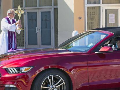 Un sacerdote bendice a un fiel que viaja en coche en Oakland Park (Florida). 