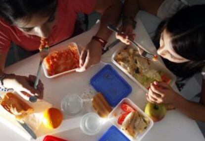 Dos ni&ntilde;as en edad escolar comen comida preparada en casa.