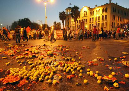 Manifestantes marchan junto a los restos de fruta que han arrojado agricultores durante las protestas en Sal&oacute;nica.