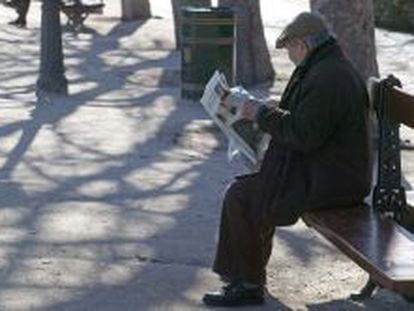Un anciano lee el periódico en un parque.