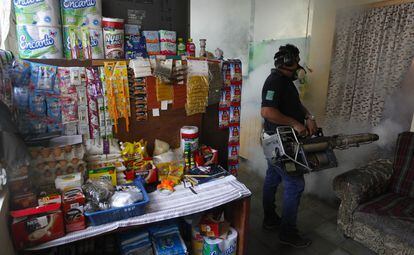 Un empleado del Ministerio de Salud de El Salvador fumiga una casa.
