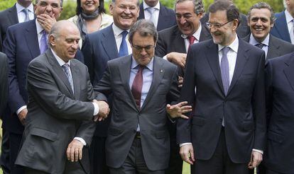 Artur Mas se situa entre el ministro del Interior, Jorge Fernández Díaz, y el presidente del Gobierno, Mariano Rajoy, en una foto de familia del Salón del Automóvil de Barcelona en mayo de 2013.