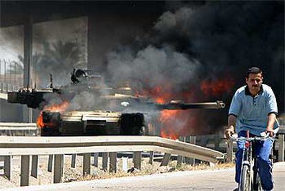 Un civil pasa junto a un blindado estadounidense Abrams en llamas ayer en el barrio bagdadí de Adhamiya.