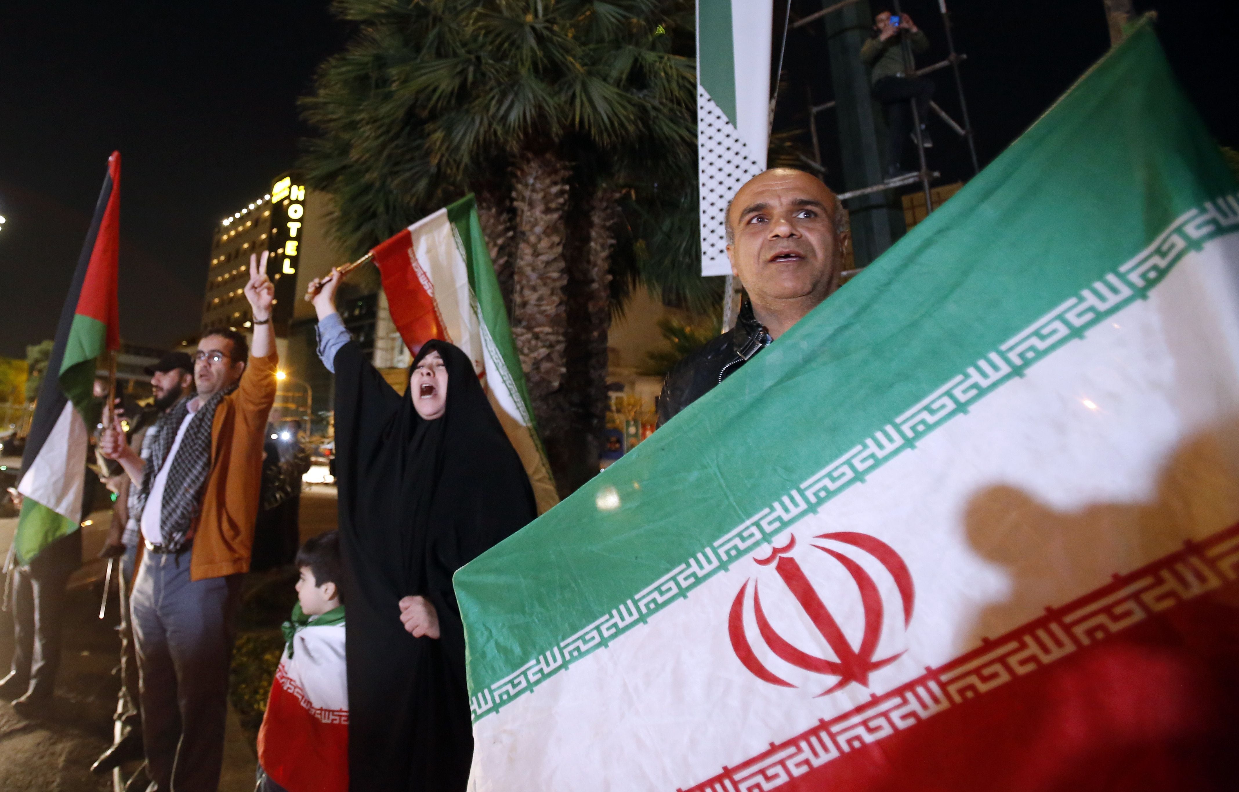 Iraníes celebran el ataque con la bandera nacional y la palestina, este domingo en Teherán.