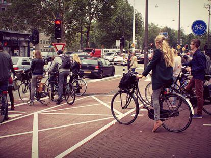 Varias personas esperan en un paso de cebra para cruzar una calle holandesa.