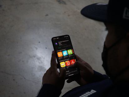 Un hombre descarga en su teléfono móvil una aplicación de préstamos que en realidad funciona como montadeudas, un tipo de extorsión telefónica.
