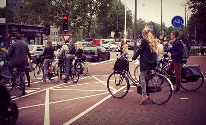 Varias personas esperan en un paso de cebra para cruzar una calle holandesa.