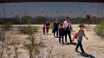 Una familia de migrantes guatemaltecos camina junto al muro fronterizo entre México y Estados Unidos, cerca de la población de Lukeville (EE UU), en agosto de 2023.