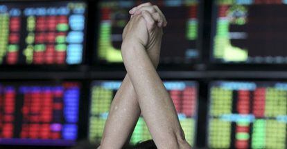 Un inversor se estira frente a unos monitores en una sociedad de inversiones en Jiangsu, China. 