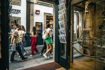 Turistas pasan delante de una entrada de souvenirs de Santiago de Compostela (A Coruña), este miércoles. 