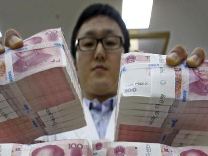 Un oficinista mueve fajos de billetes de 100 yuanes chinos a lugar seguro en la sede del Korea Exchange Bank en Se&uacute;l (Corea del Sur). 