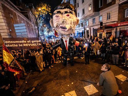 Un hombre se dispone a golpear un muñeco con la figura de Pedro Sánchez en la protesta cerca de la calle de Ferraz, en Madrid, en Nochevieja.