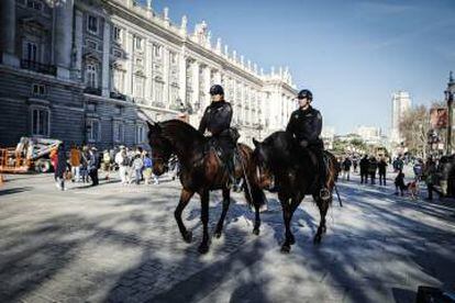 Dos policías a caballo pasan por delante del Palacio Real.