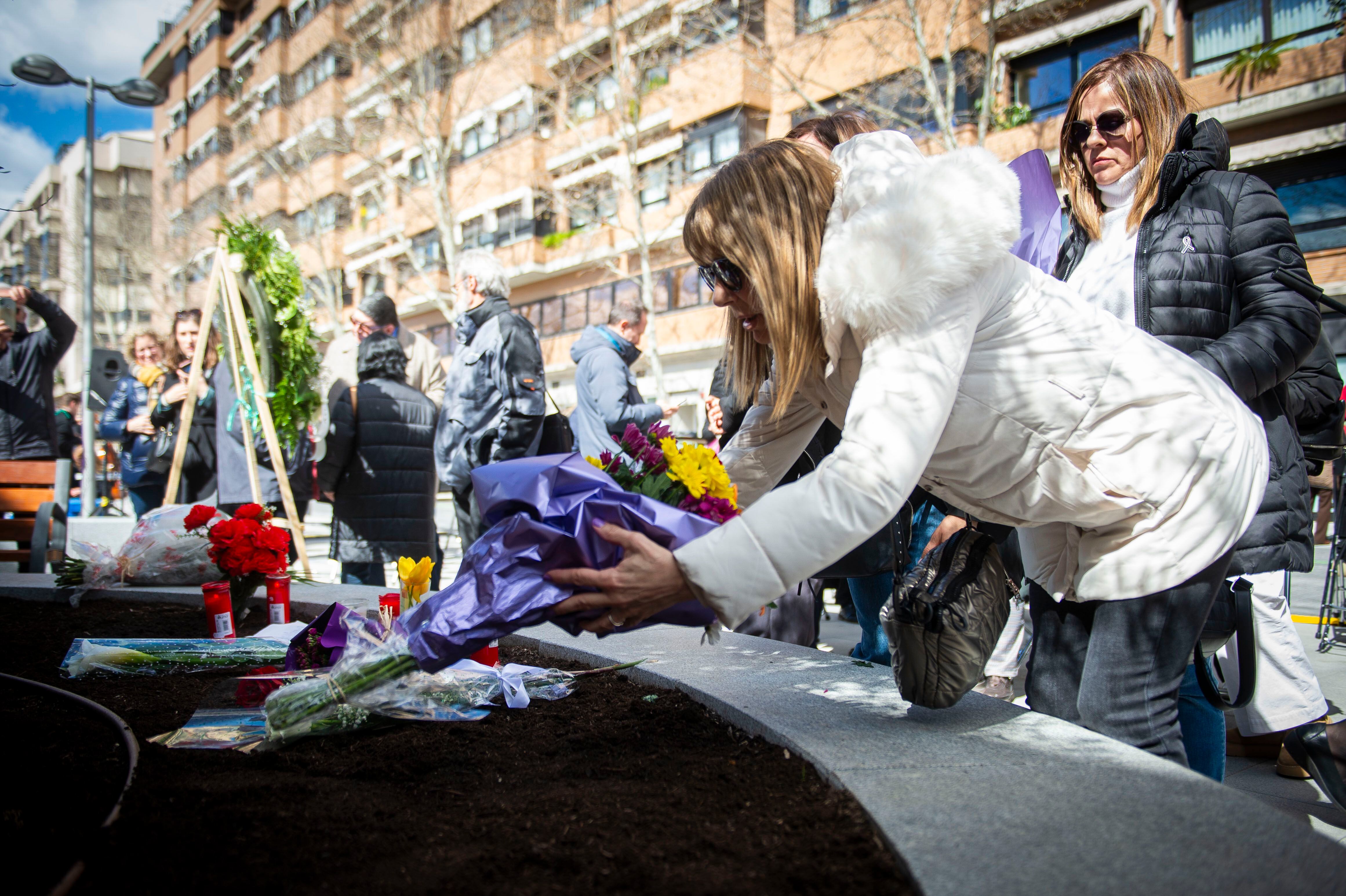 Una mujer deposita flores en el homenaje en la calle de Téllez, durante el aniversario de 20 años de los atentados terroristas de Madrid.