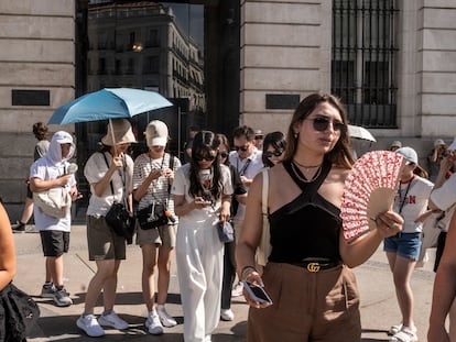 Varios turistas se protegen del sol con sombreros y paraguas ante la falta de sombra en la Puerta del Sol de Madrid, el lunes.