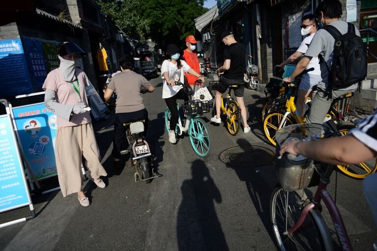 Una trabajadora social comprueba la temperatura de varias personas en una calle de Pekín.