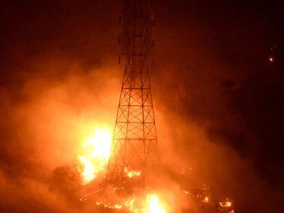 Las llamas del incendio Thomas consumen una torre de alta tensión en Montecito, California.