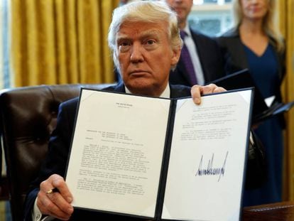 Donald Trump muestra su firma sobre una orden ejecutiva. 