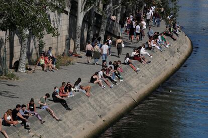 Personas sentadas a la orilla del Sena, en París, el domingo.